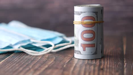 rolled up $100 bill next to medical masks
