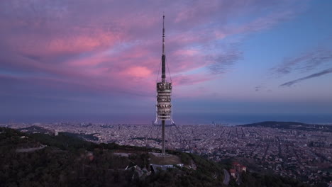 cinematic view of collserola tower at sunset on tibidabo with barcelona city in background, spain