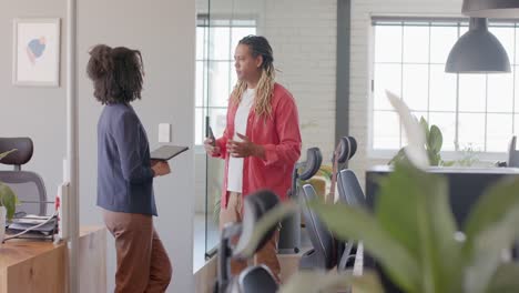happy diverse casual business colleagues using tablet and talking standing in office, slow motion