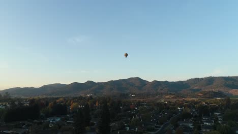 fall back aerial of hot air balloon rising over small town in the napa valley
