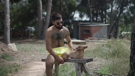 a man petting his dog while relaxing on a bench outdoors