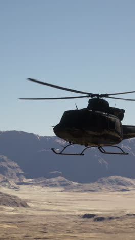 military helicopter flying over desert landscape