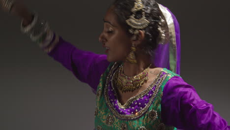 Close-Up-Of-Female-Kathak-Dancer-Performing-Dance-Wearing-Traditional-Indian-Dress-Seated-On-Floor-In-Spotlight-3