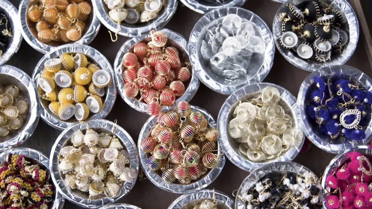 un pequeño conjunto de piezas de joyería y aretes colocados en pequeñas tazas diferentes para la venta