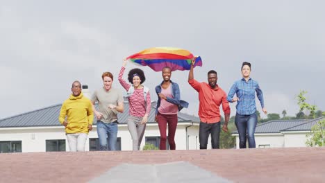 happy group of diverse male and female protesters walking with rainbow flag