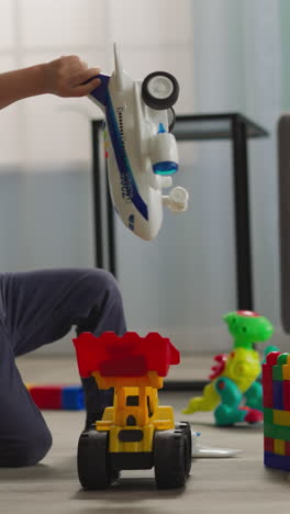 blond toddler plays with airplane and transportation toys while preschooler sister building constructor. cute boy spends time with elder sister closeup