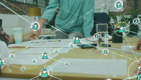 animation of connected icons over diverse coworkers discussing reports in office
