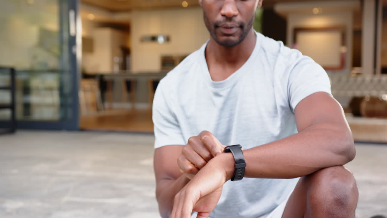 Checking smartwatch, african american man in casual wear sitting at home, at home, copy space