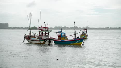 vibrantes y tradicionales pequeñas embarcaciones de pesca flotando suavemente cerca de la costa en un día nublado por aguas tranquilas, reflejando la cultura serena pero laboriosa de los medios de vida costeros.