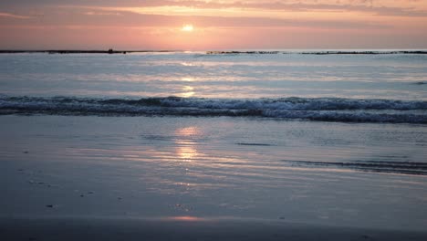 El-Amanecer-Se-Refleja-En-Las-Olas-Cuando-Llegan-A-Una-Playa-Tranquila-En-Cámara-Lenta