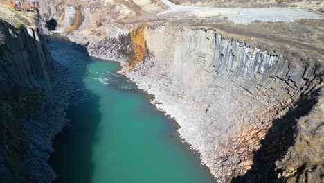 Beautiful-aerial-drone-forward-moving-shot-over-Studlagil-canyon-in-iceland-with-Basalt-columns-along-the-Icelandic-landscape