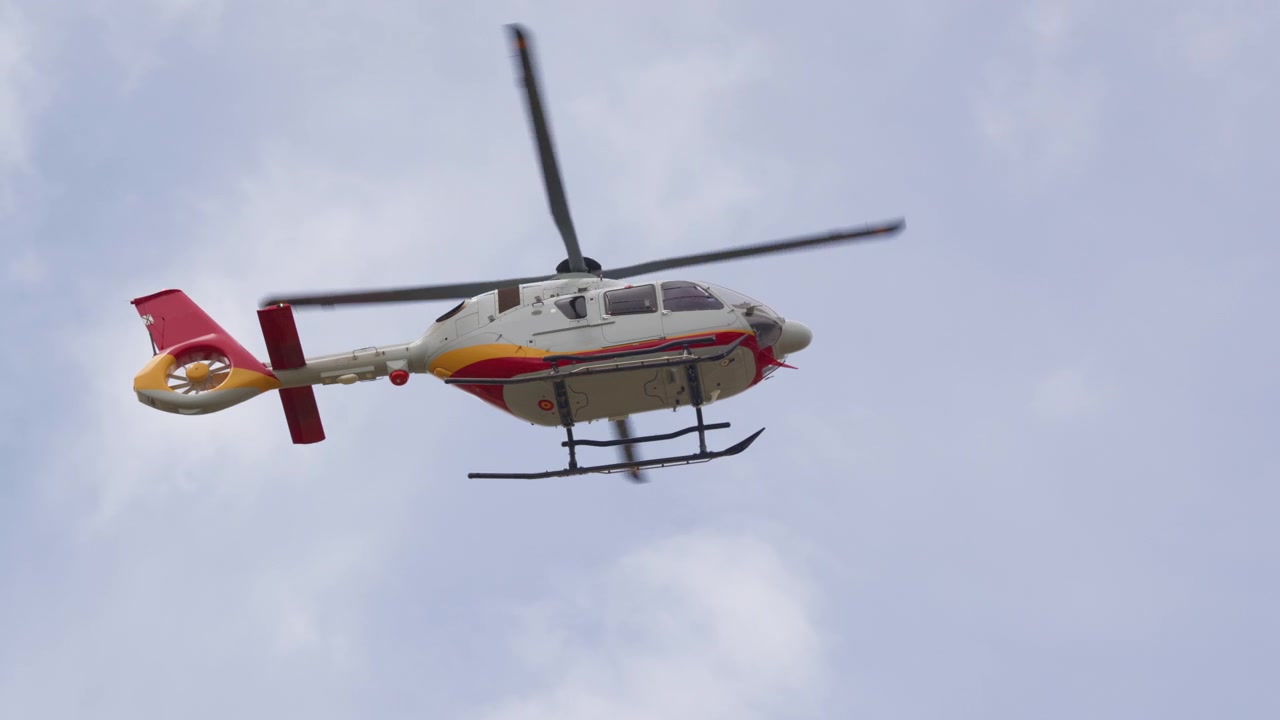 Hvid og rød helikopter flyver mod en skyet himmel