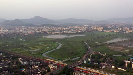 Vista-Aérea-De-Carreteras-Y-Ferrocarriles-En-Vasai-Cerca-De-La-Ciudad-De-Mumbai-En-India-En-Una-Puesta-De-Sol-Brumosa