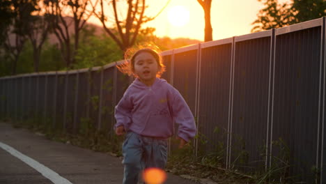 little girl runs in slow motion with sun setting behind mount