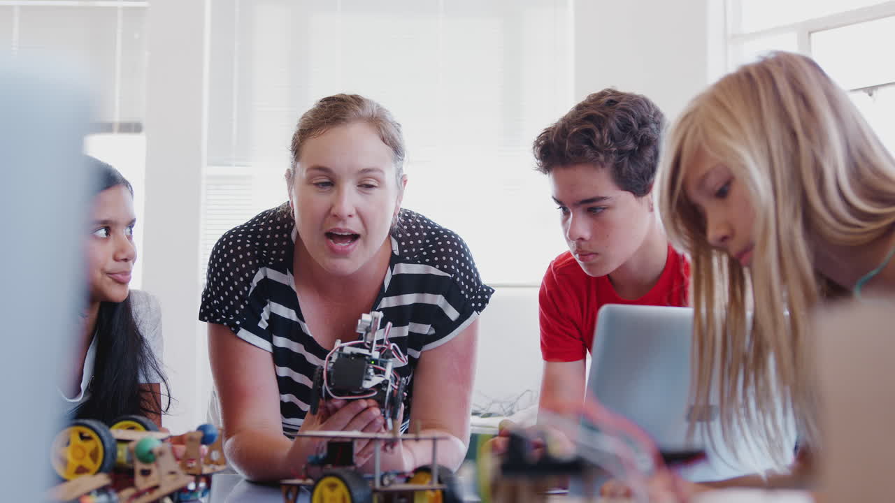 Students With Female Teacher In After School Computer Coding Class Learning To Build Robot Vehicle