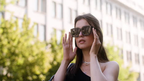 young fashionable woman putting the sunglasses on in the street