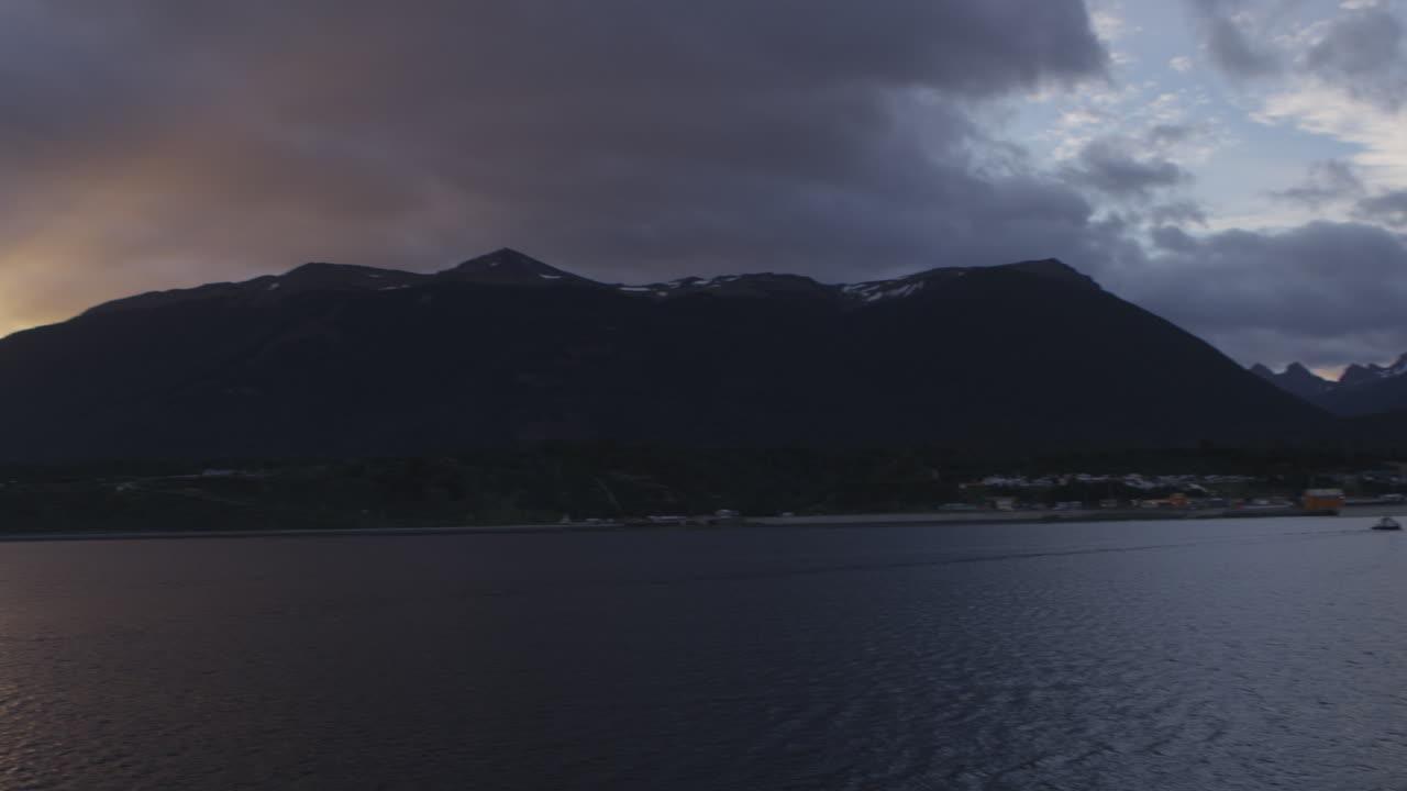 Città sull'oceano con montagne sullo sfondo, tramonto