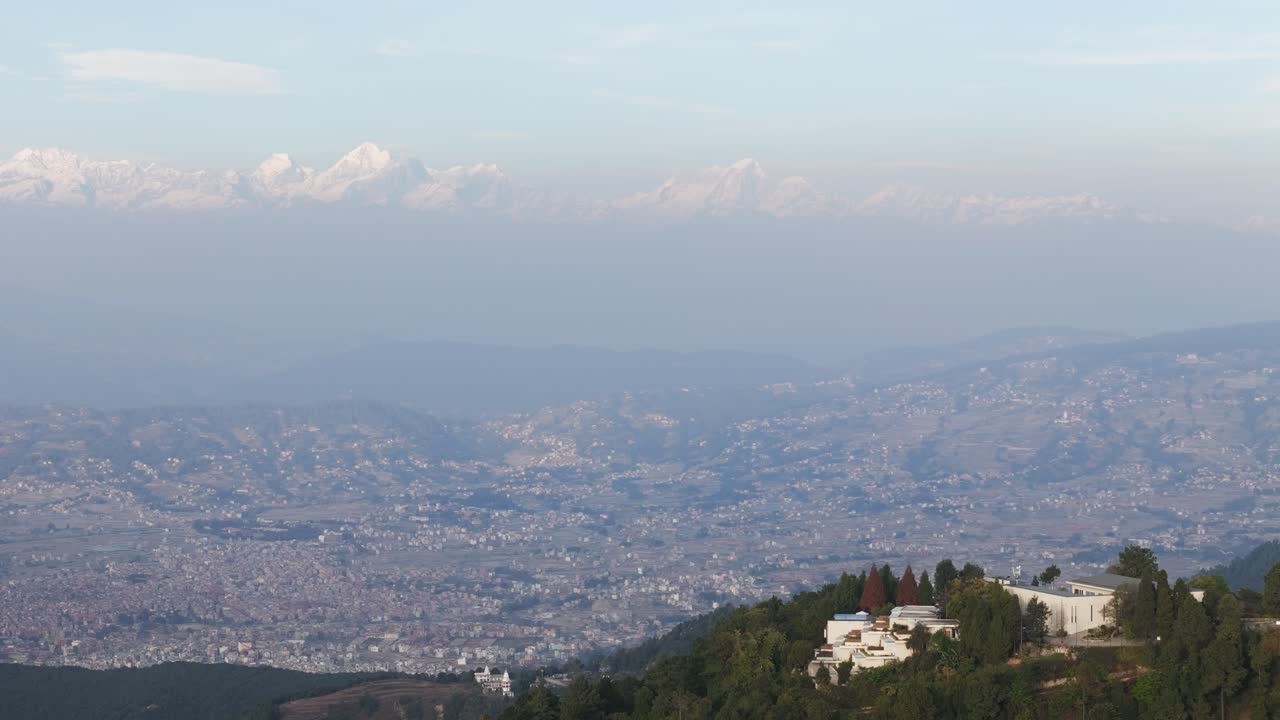 Drone view of Kathmandu Valley revealing its dense urban layout, surrounding green hills, and distant Himalayan horizon, capturing the unique blend of culture, terrain, and city life in Nepal