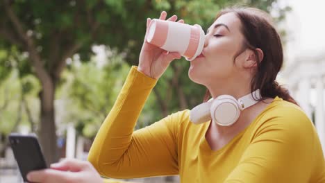 young caucasian woman drinking coffee while being on phone