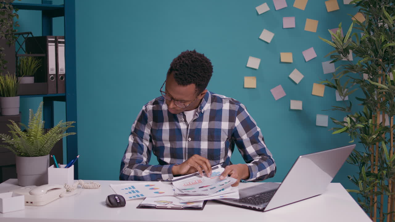 Young business man sorting out financial charts on papers