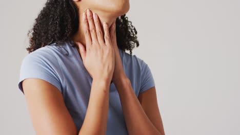 Video-of-biracial-woman-touching-her-neck-on-white-background