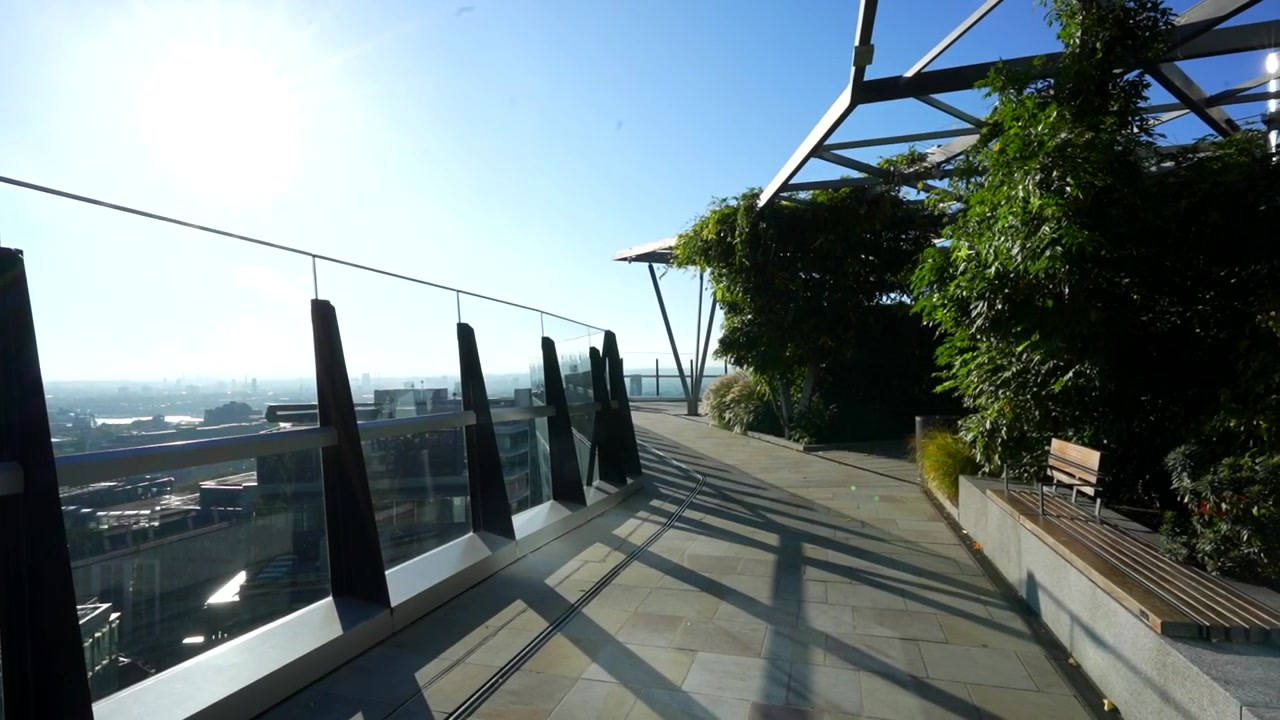 Giardino pensile con pannelli di vetro che offre vista sulla città in un grattacielo soleggiato a Londra.