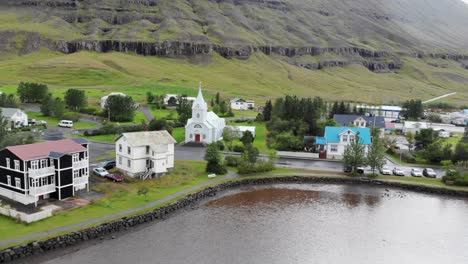 aerial flying over seydisfjordur villege in iceland with a small church