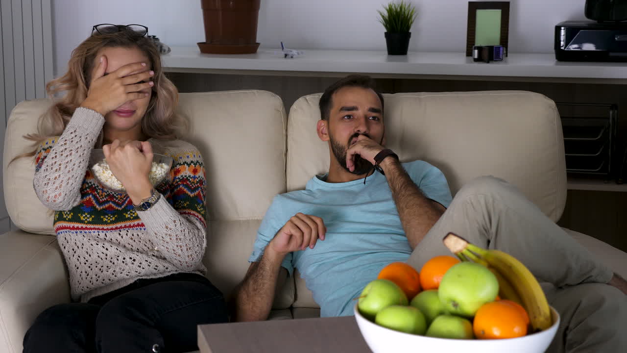 Coppia guarda la TV con popcorn e frutta