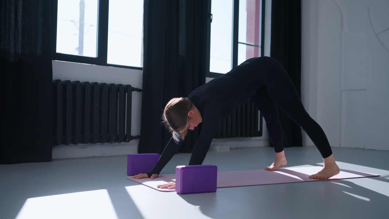 mujer haciendo yoga en una alfombra con bloques
