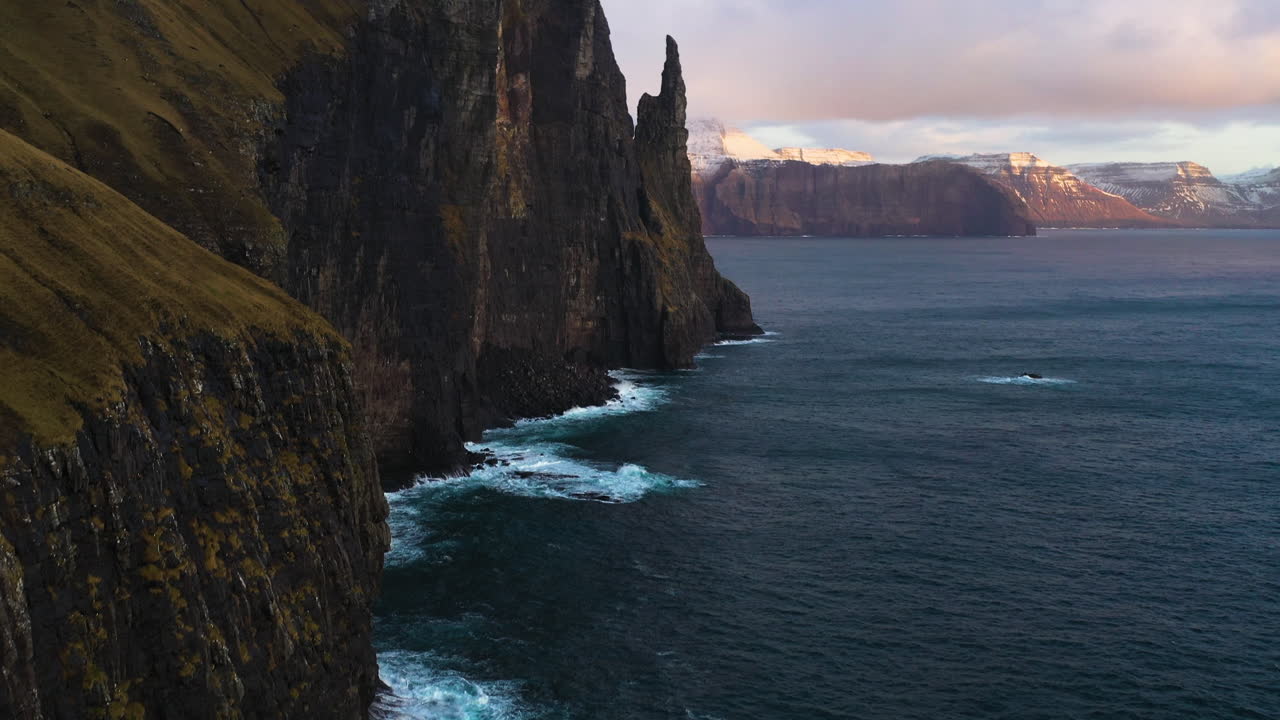 Aerial view following the steep coast of Traelan&iacute;pan, the Slave Mountain, sunset in Faroe islands