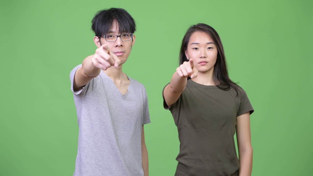 Young Asian couple pointing at camera