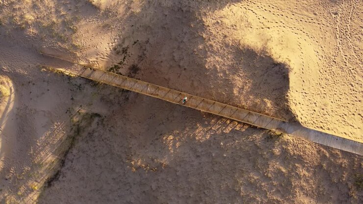 Aerial overhead shot of person crossing a wooden bridge at the entrance of the beach in Punta del Este City