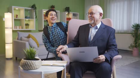 the naughty grandson scares his grandfather who does his work from the laptop and they joke.