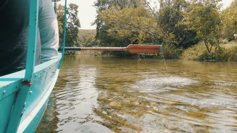 People-traveling-on-a-boat-with-an-oar-paddling-through-the-crystal-clear-water-of-a-natural-lake