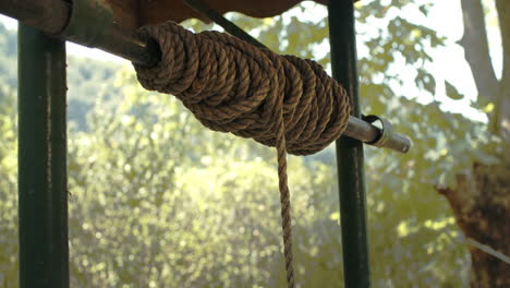 close up of vintage rope and drawing water from old well with iron bucket in slowmo