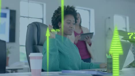 Yellow-upward-arrows-over-diverse-female-colleagues-discussing-at-desk-in-casual-office