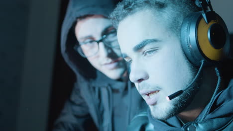 two young guys actively discussing something while hacking in dark room at night