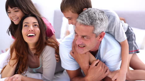 padres y sus hijos jugando en la cama