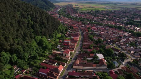 Ciudad-De-Rasnov-Con-Bosques-Y-Casas-Durante-El-Día,-Vista-Aérea