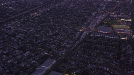 Aerial-Establishing-Shot-over-Residential-Neighborhood-Area-tilt-up-revealing-Downtown-Los-Angeles,-California-Skyline-from-Culver-City-at-Dusk,-Night-with-Purple-Sky,-wide-angle