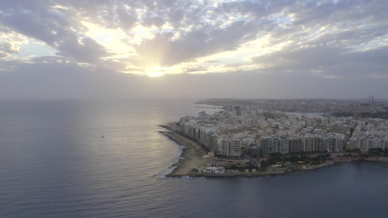 Cloudy morning at malta seaside. Video shows the houses and very calm sea with sun shinning through the clouds.