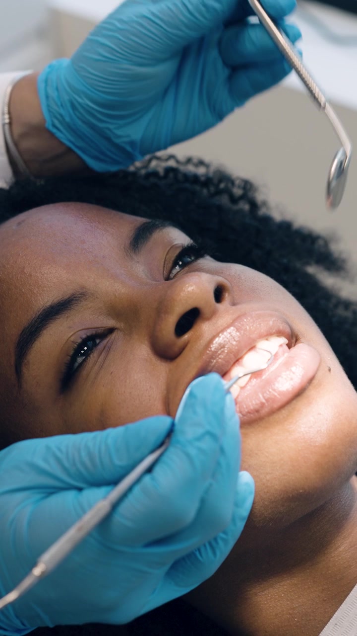 Dentista Examinando os Dentes de Jovem Mulher em Clínica Dentária