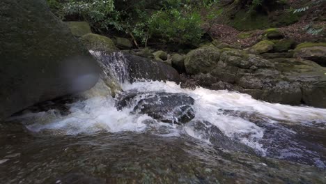 corriente de montaña en movimiento lento chocando contra las rocas