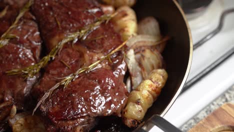 delicious roasted beef in pan with potatoes, onions, and rosemary leaves