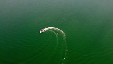 Luftdrohne-überfliegt-Ein-Boot,-Das-Mit-Einem-Schlauchboot-Schleppt,-Dessen-Fahrer-Ins-Wasser-Fallen