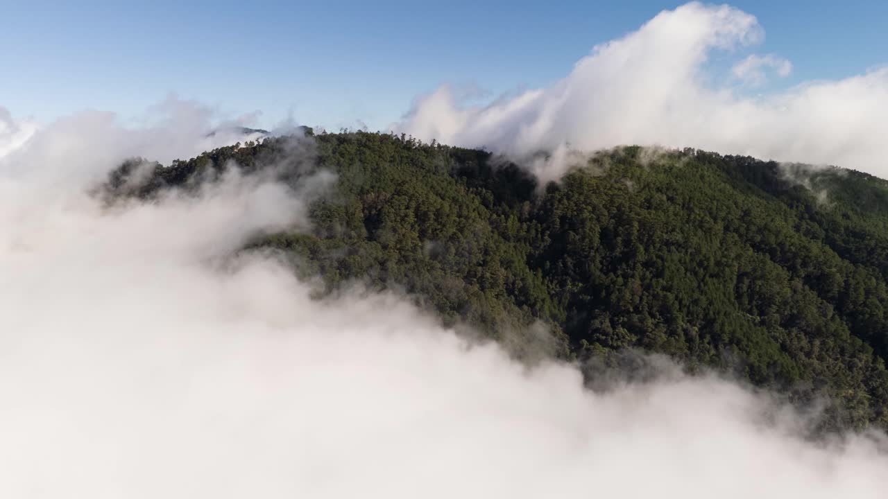 Aerial time-lapse of fast-moving clouds sweeping over a forested mountain near Zacatlan as the drone holds position above the ridge