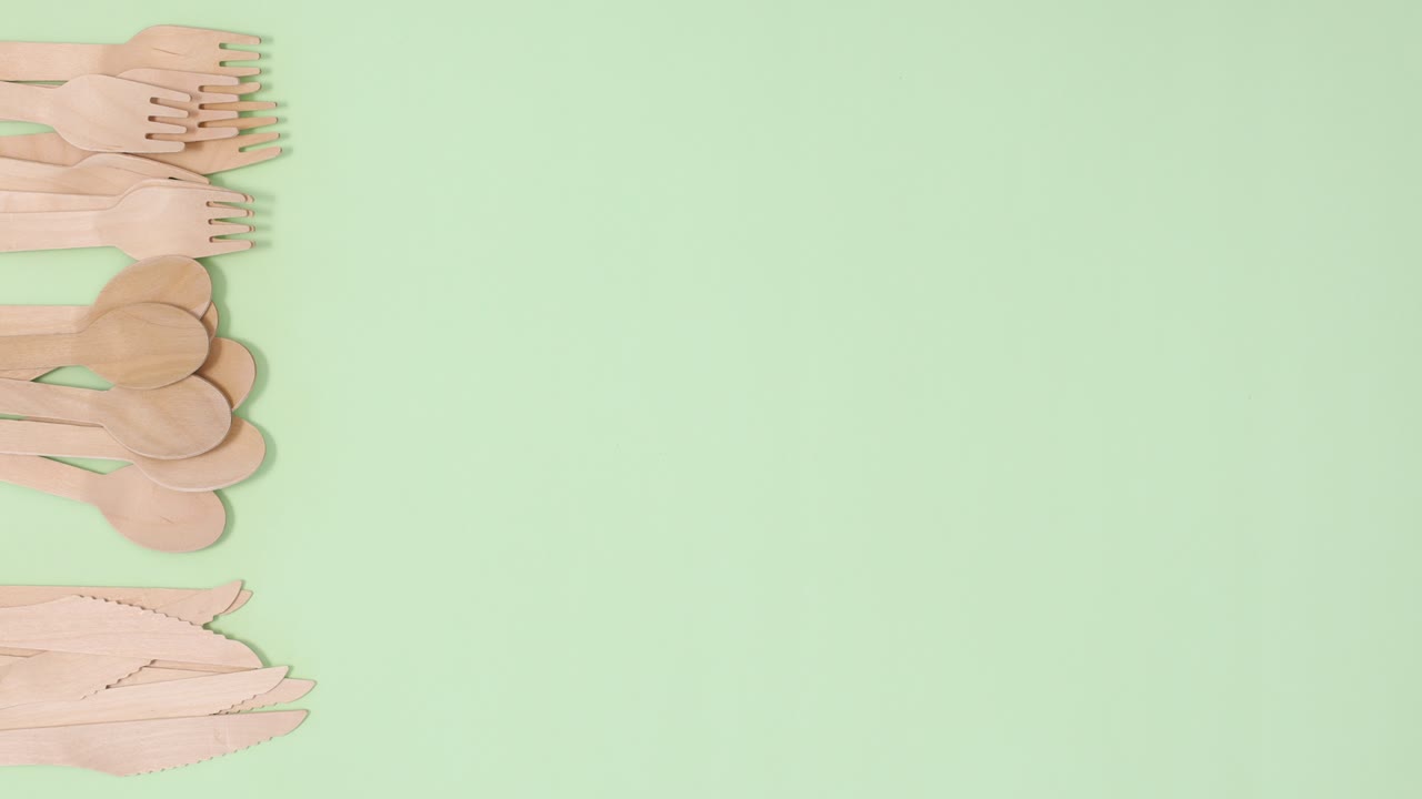 Pile of eco friendly zero waste spoons, forks and knifes appear on left side. Stop motion flat lay