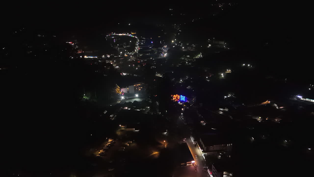 Panoramic drone shot overlooking illuminated streets of Munnar, night in India