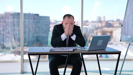 tired businessman showing various expressions of his face. office worker sitting at the table on window background.
