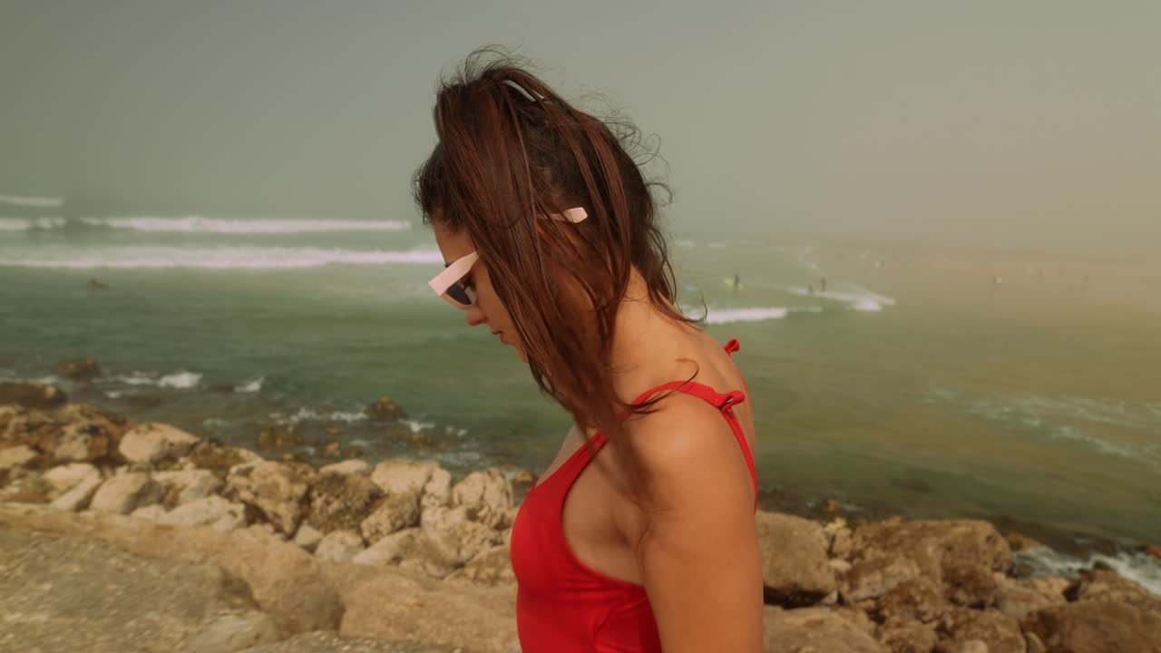 Giovane donna che cammina lungo la costa rocciosa della spiaggia